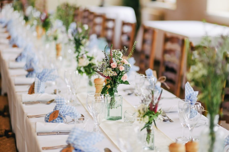 A long reception table set with linen and low floral arrangements, empty before guests arrive.